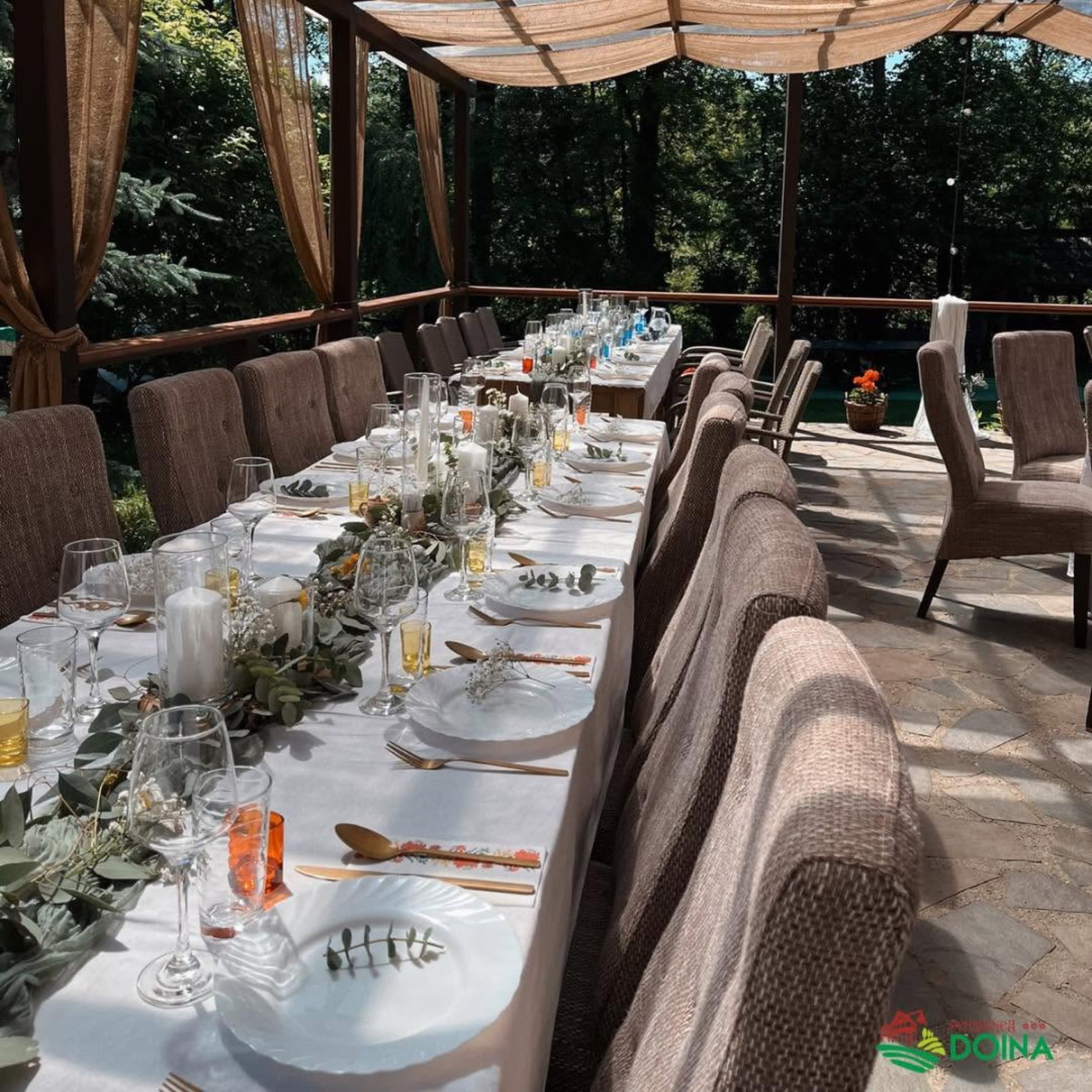 Masă elegantă întinsă sub pergolă, pentru o sărbătoare